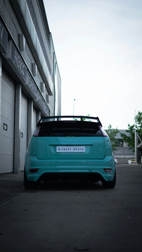 a teal car parked in front of a garage