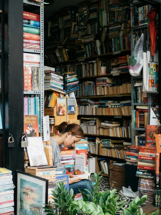 a woman sitting at a table in front of a book shelf filled with books