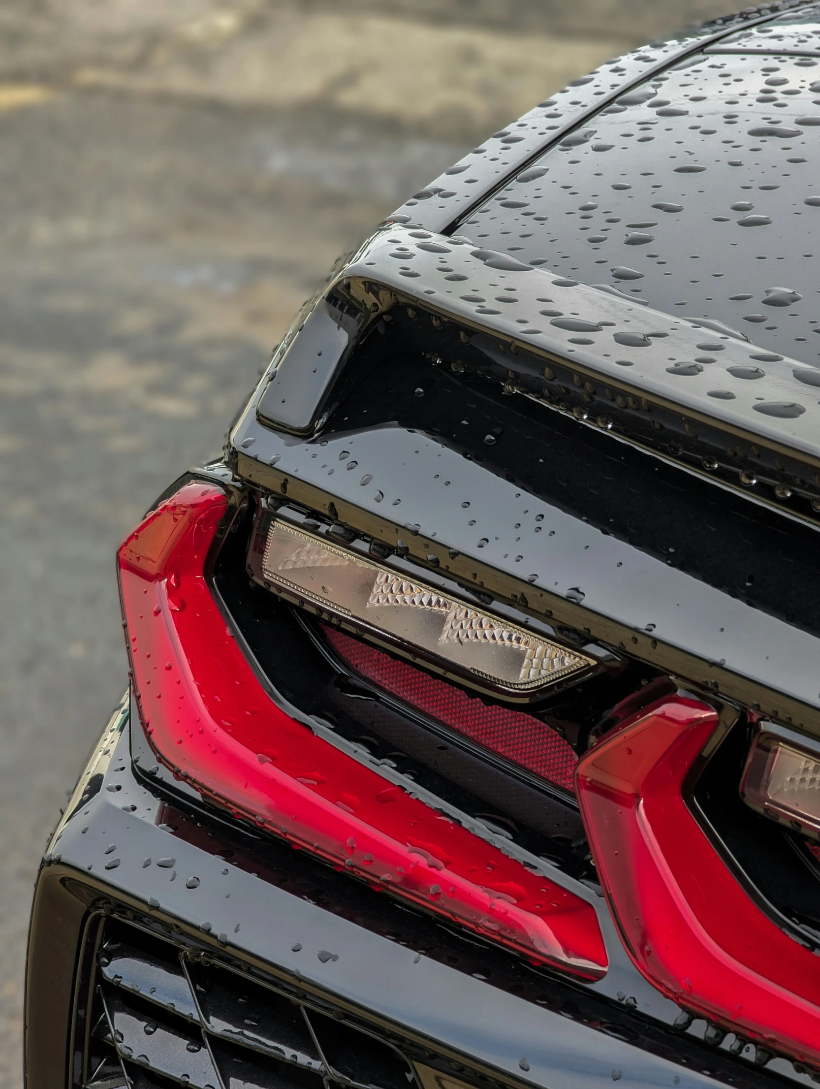 the taillight of a black car with rain drops