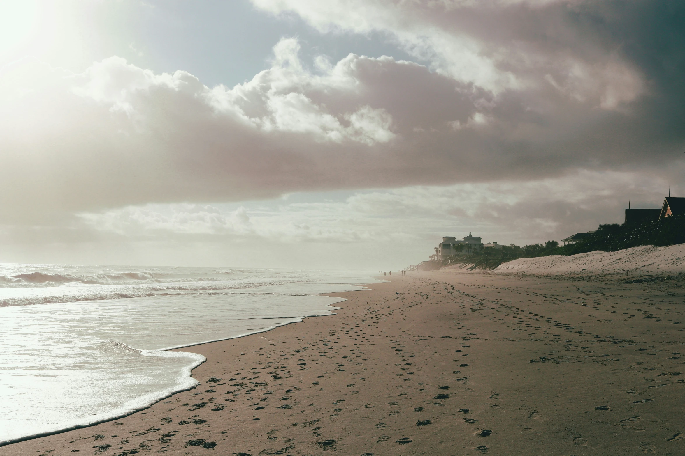 an ocean view of a sandy beach with footprints in the sand