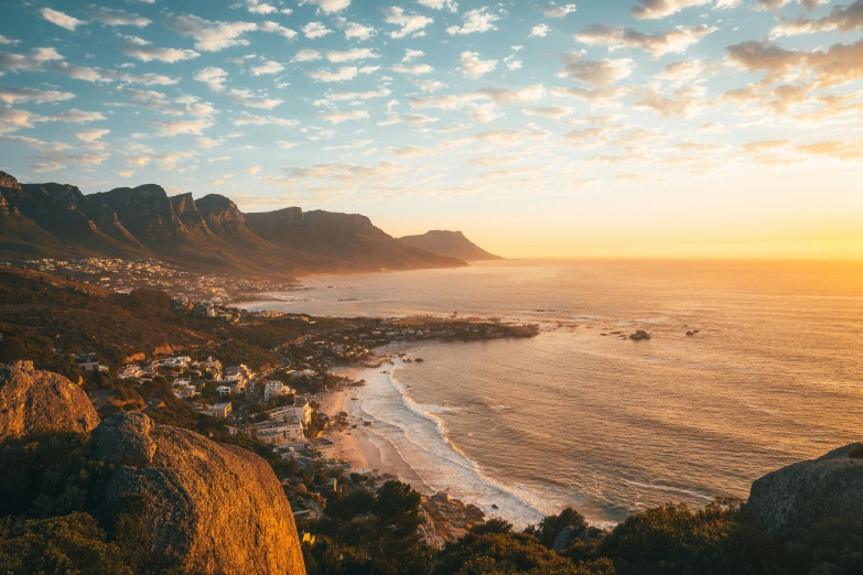 the sun shines brightly on the beach below a mountainous area