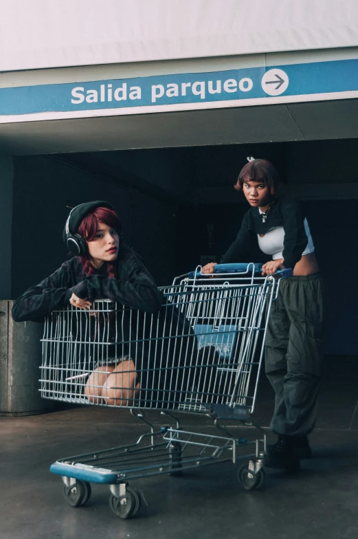 two woman sitting in a shopping cart with a man standing by
