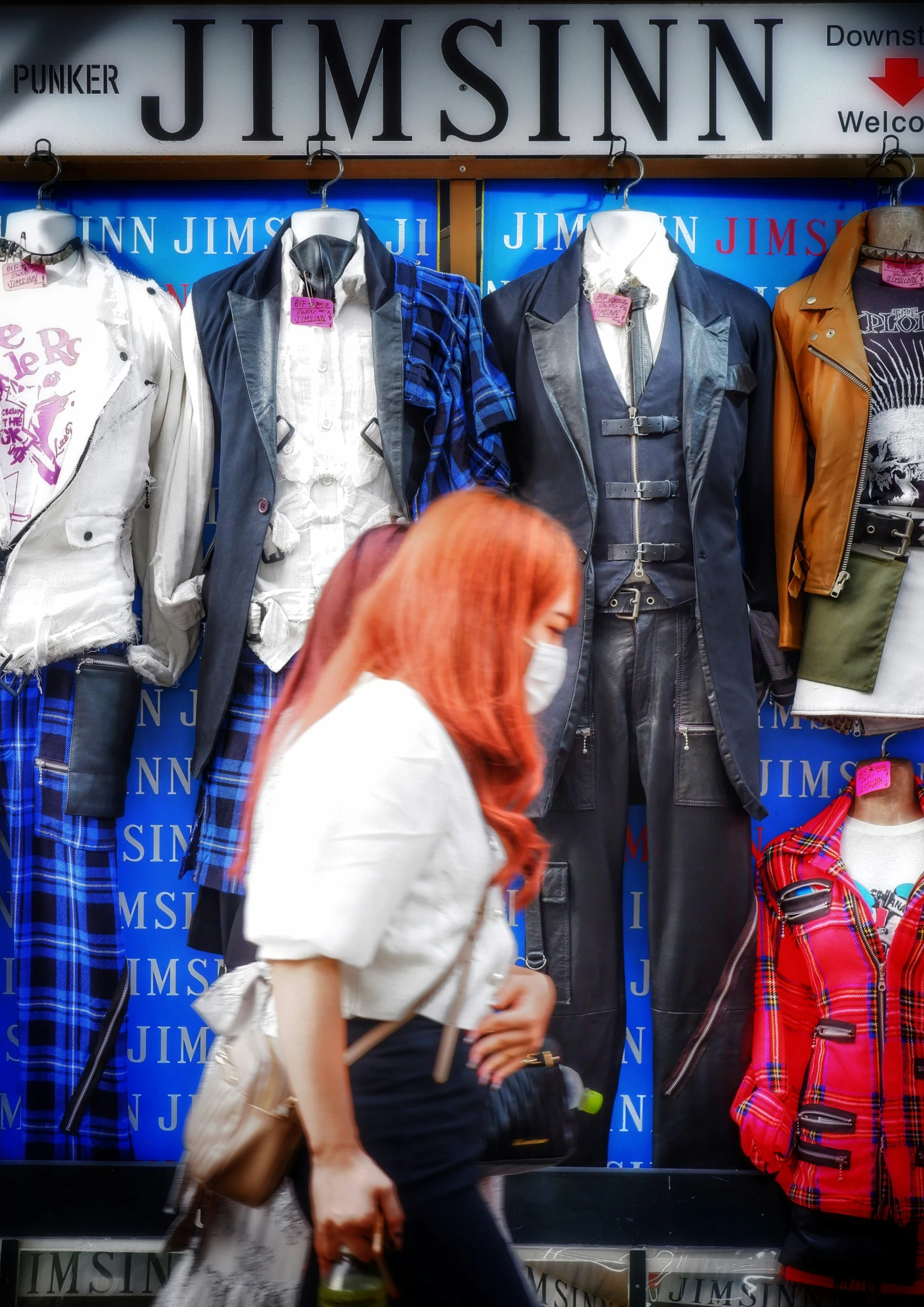 the young woman walks past some mannequins in front of a clothing store