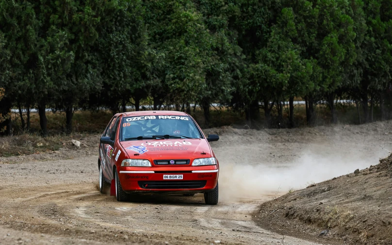 a red car kicking up dust on a dirt road