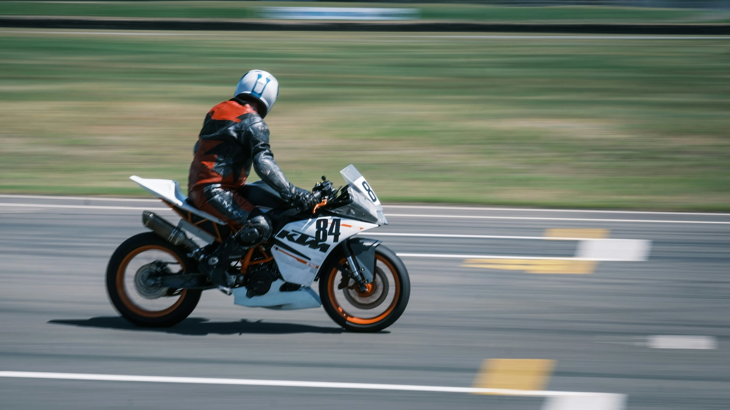 man riding motorcycle down the street in front of grassy area