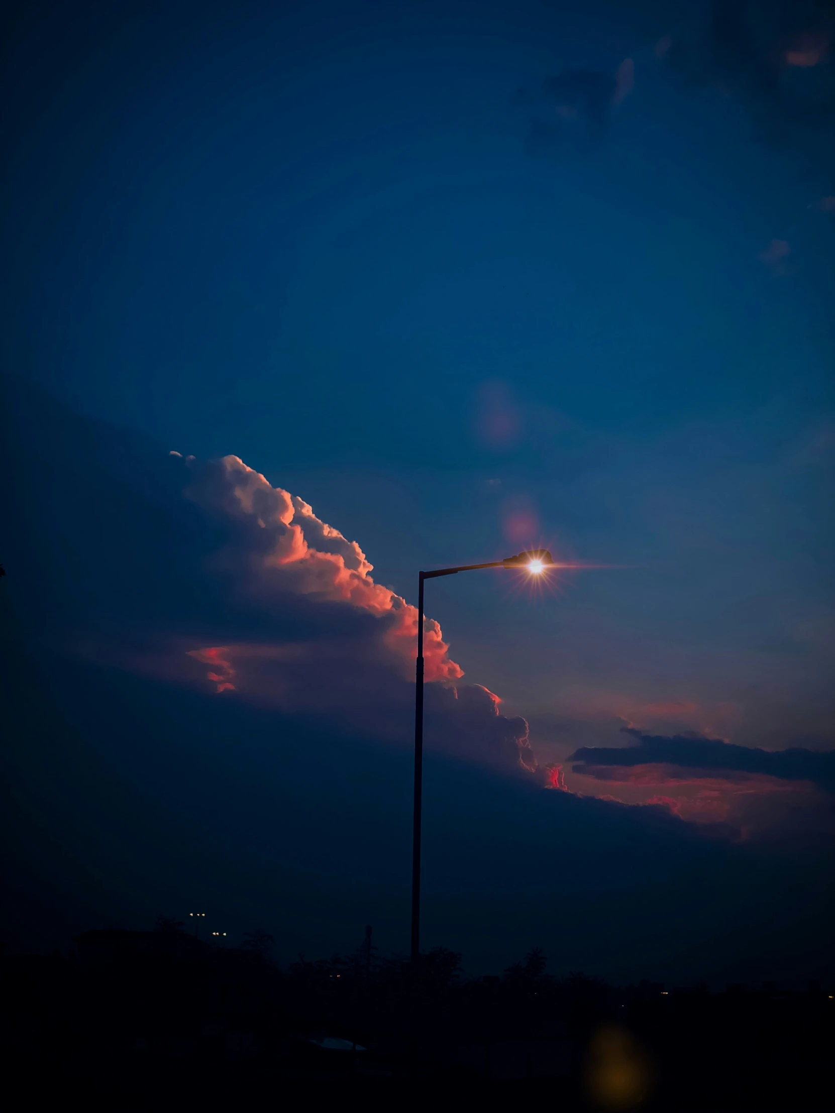 a tall pole holding a street lamp and a bright light