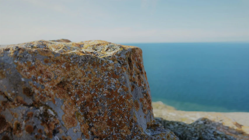 rocks with sand splatters on them on the top of a cliff overlooking the water