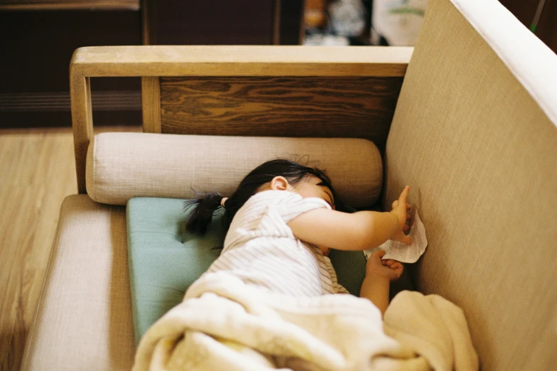 a girl lying on top of a bed next to a chair