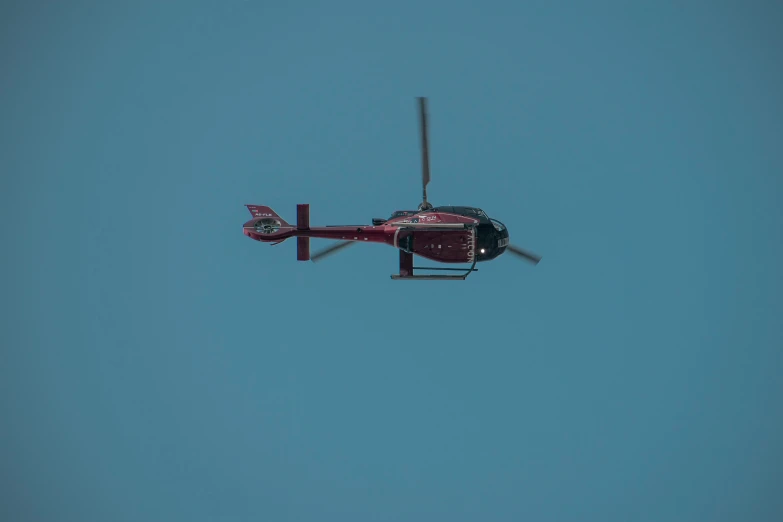 a helicopter flies high above the blue sky