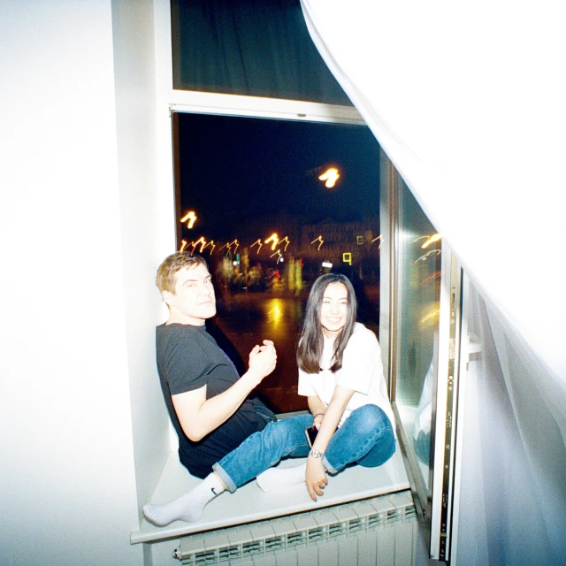 two people are sitting on the ledge of a building