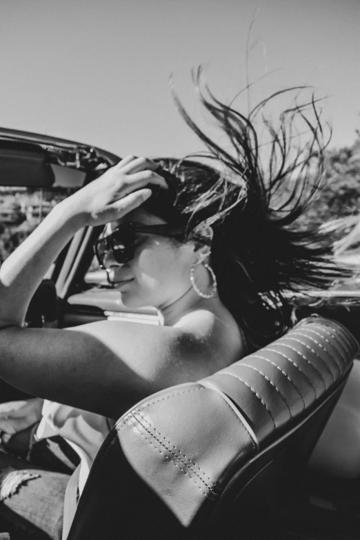 a black and white po of a woman sitting in the drivers seat of a car