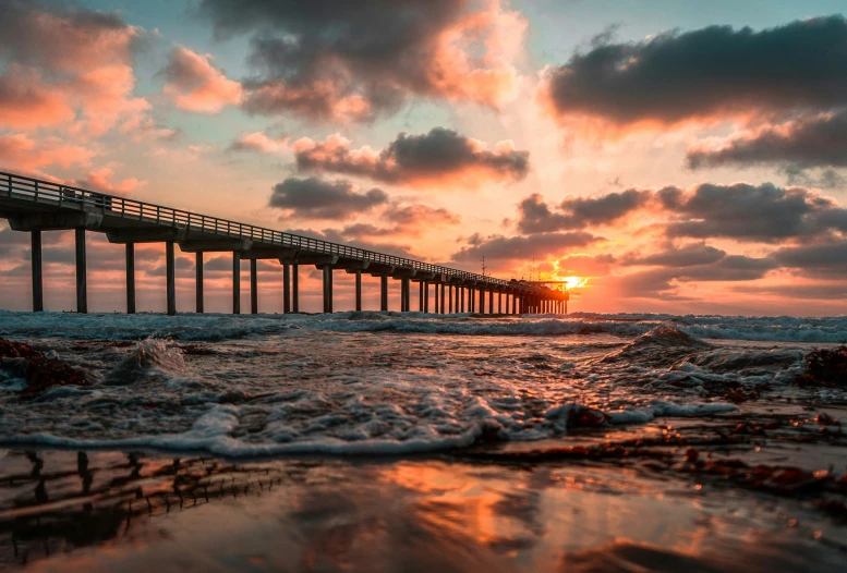 a pier sitting next to the ocean at sunset