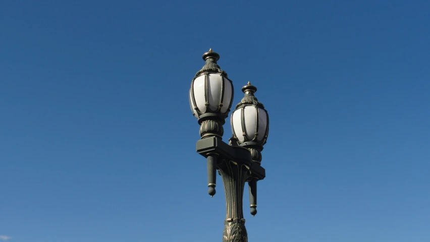 two white street lamps against a blue sky