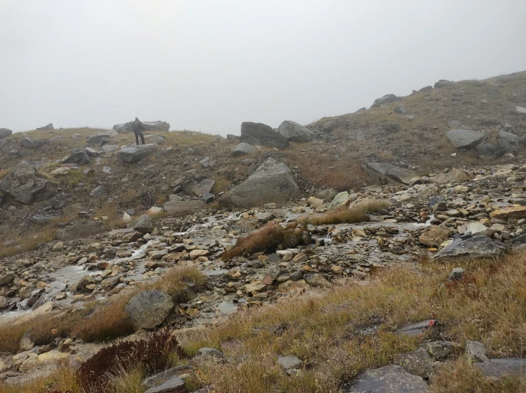 a man walking up a mountain near some rocks