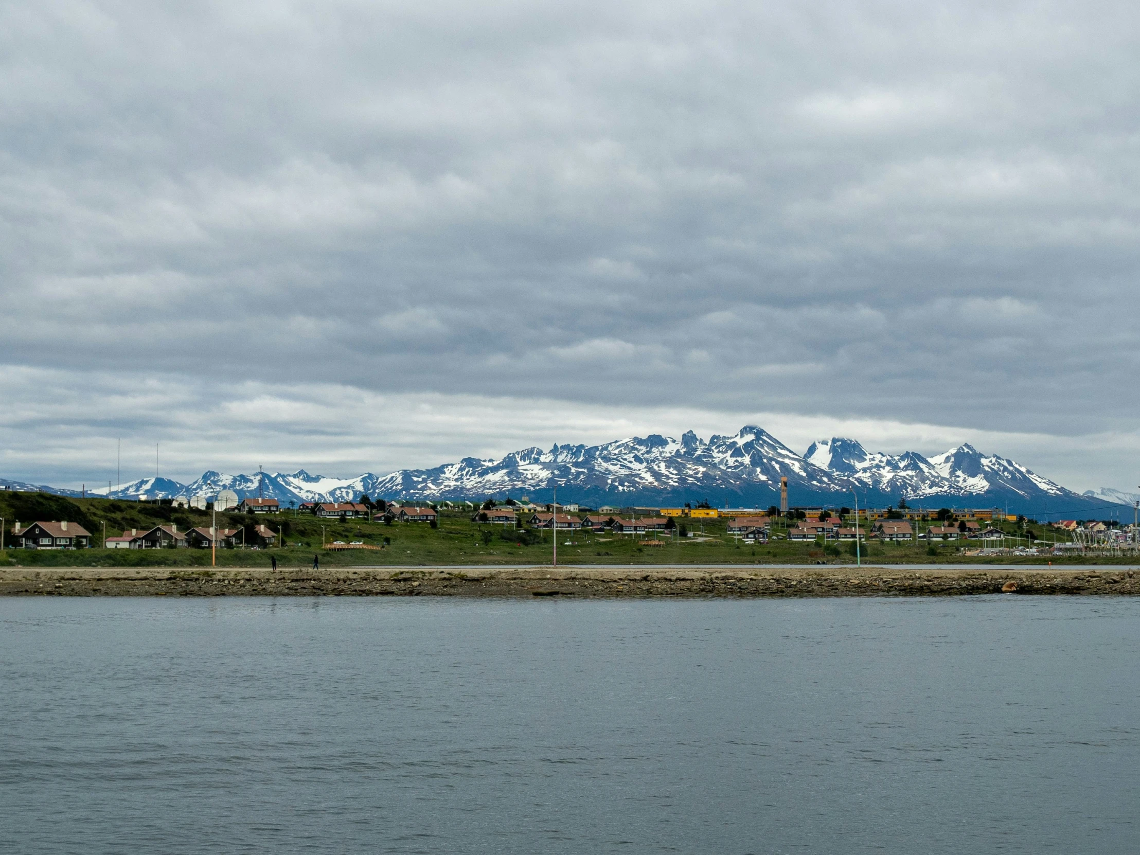 there are mountains behind the water and houses