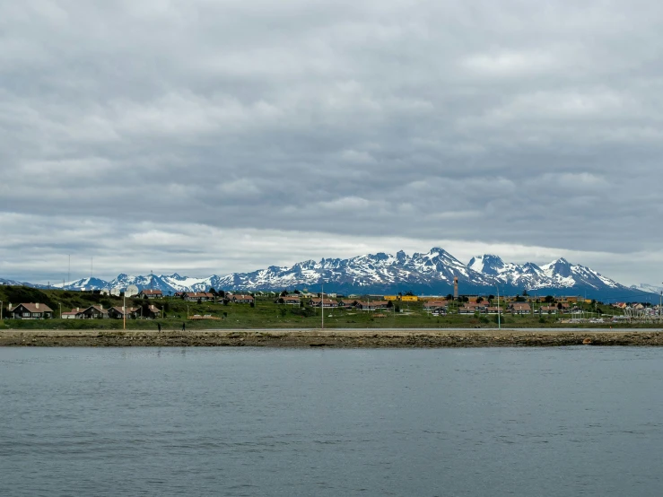 there are mountains behind the water and houses