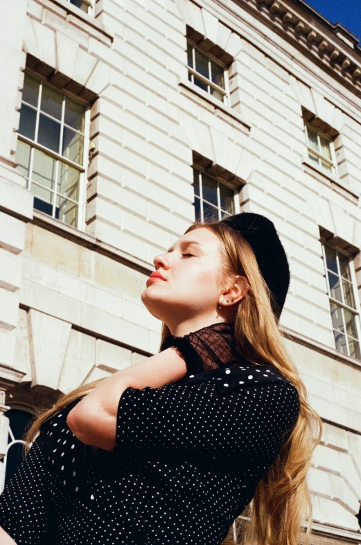 a woman is wearing a hat while standing outside of a building