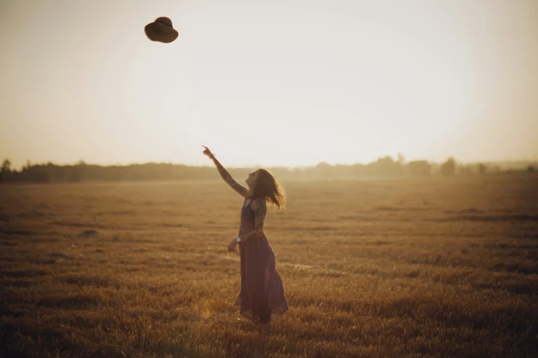 a woman standing in a field flying a kite