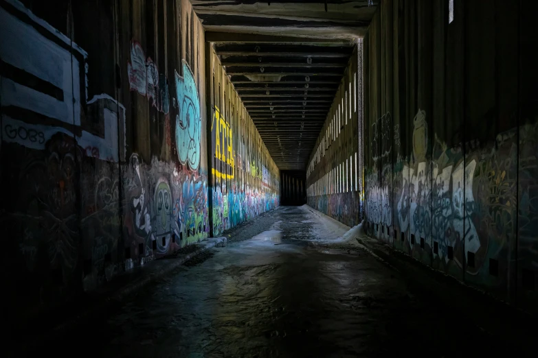 a tunnel with graffiti on it and one wall near the road