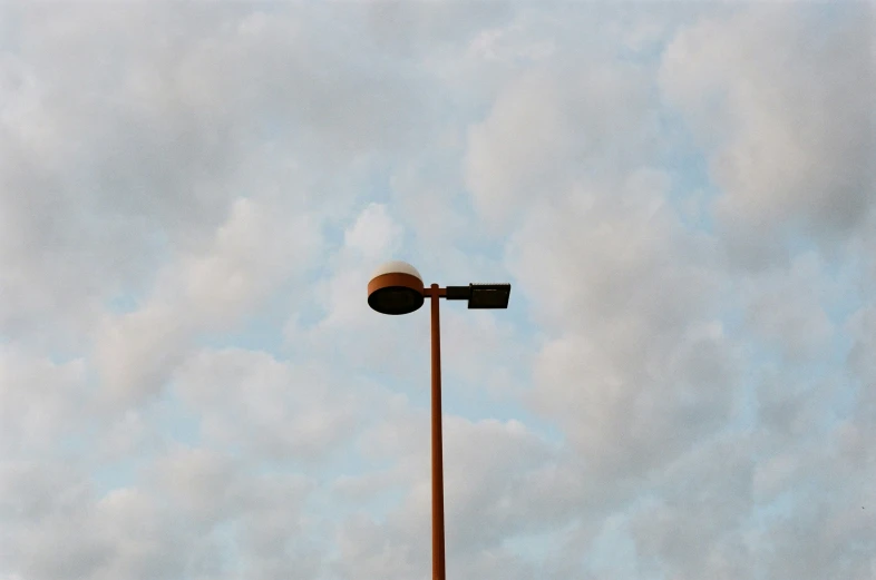 the top of a street light against a cloudy sky