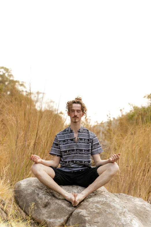 a man sitting on a rock in a meditation pose