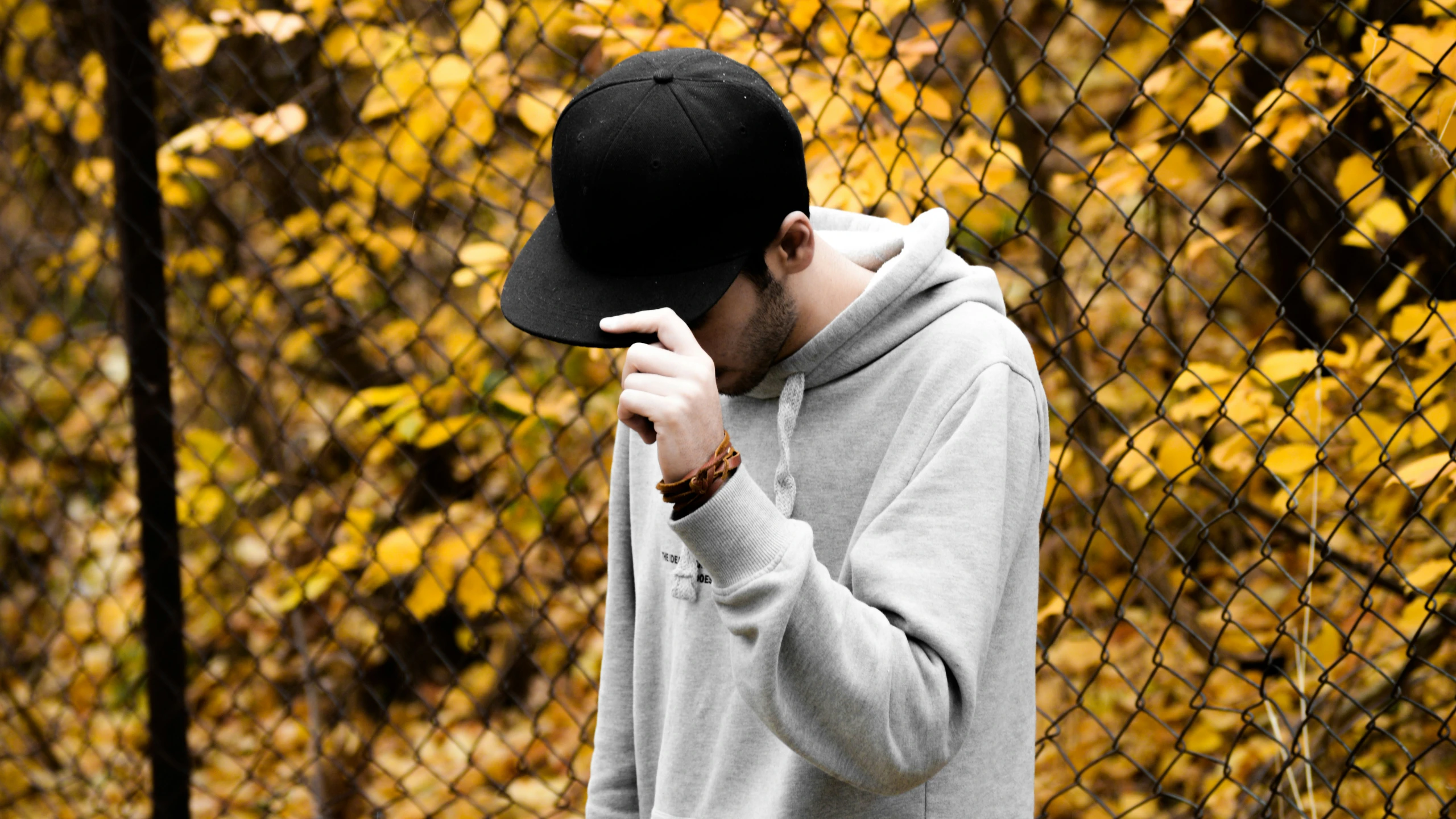 a man in a hat is standing next to a fence