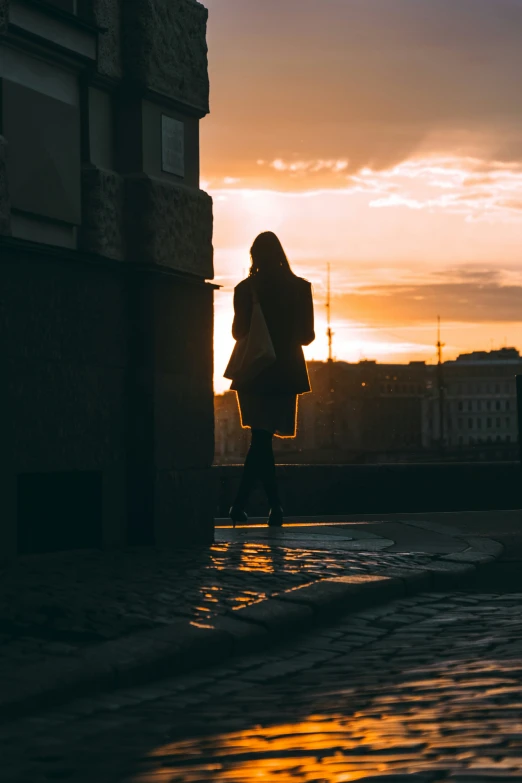 a silhouetted person walking down a sidewalk carrying shopping bags