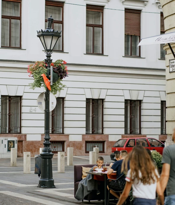 two people sitting at a table in the middle of a plaza with a street light