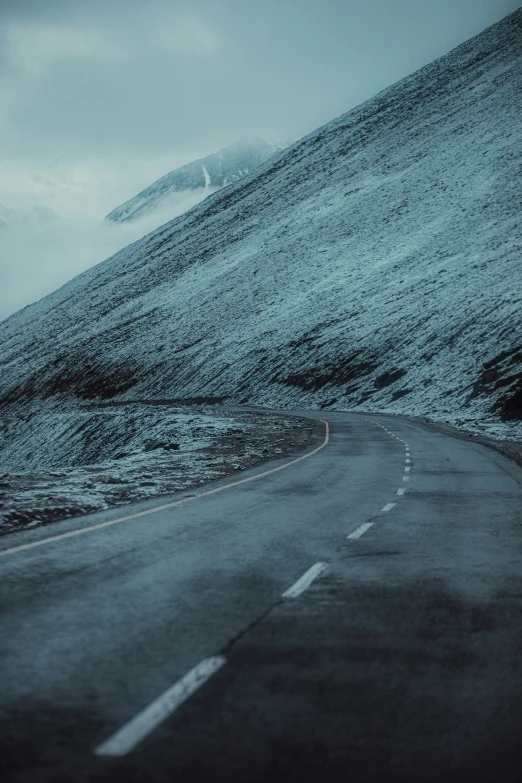 a road on a hilly mountain has some fog