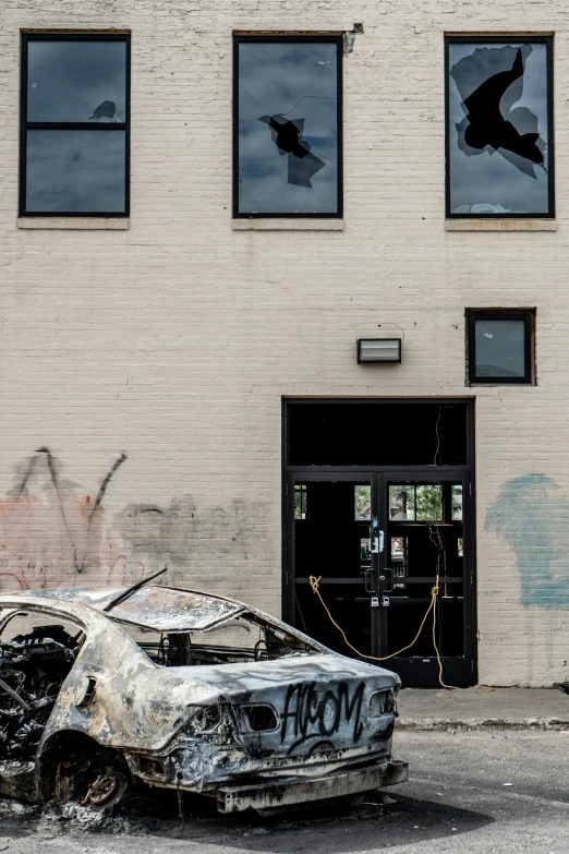 a burnt car on a street next to buildings