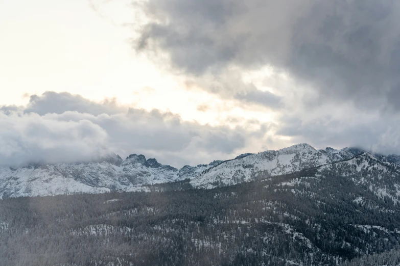 the mountains are covered in snow and clouds