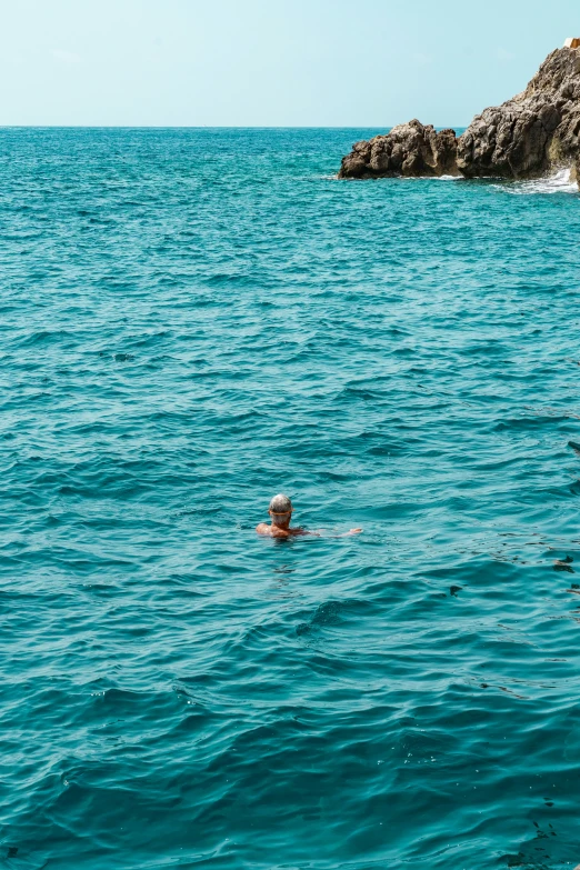 a person floating in the ocean surrounded by rocks