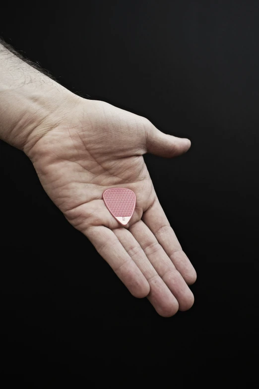 a pink heart shaped ring on a mans hand