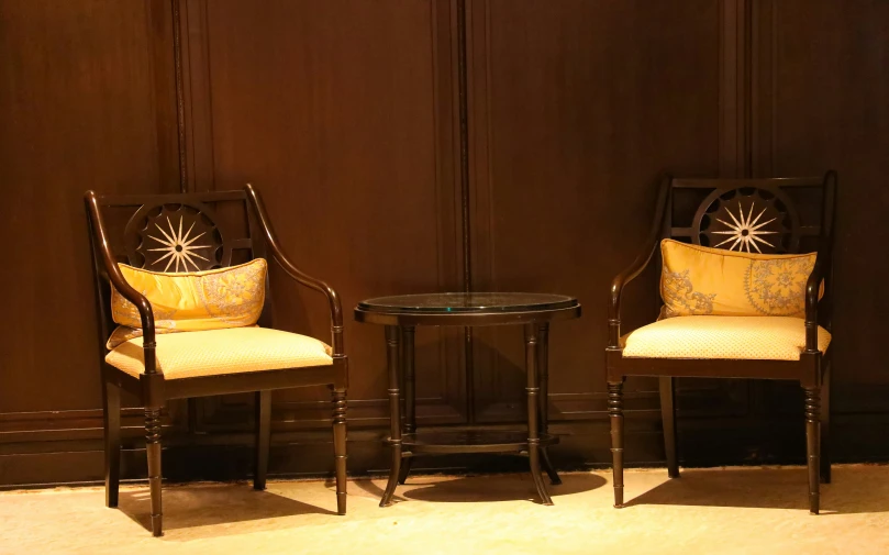 two chairs sitting against a wall with a side table in front of them