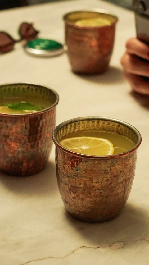 three small metal cups with yellow liquid in them