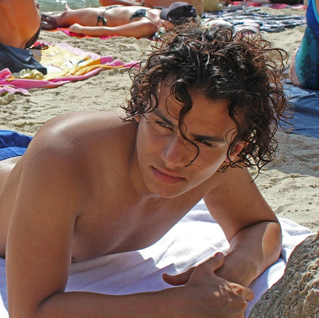 a guy lying on the beach wearing 