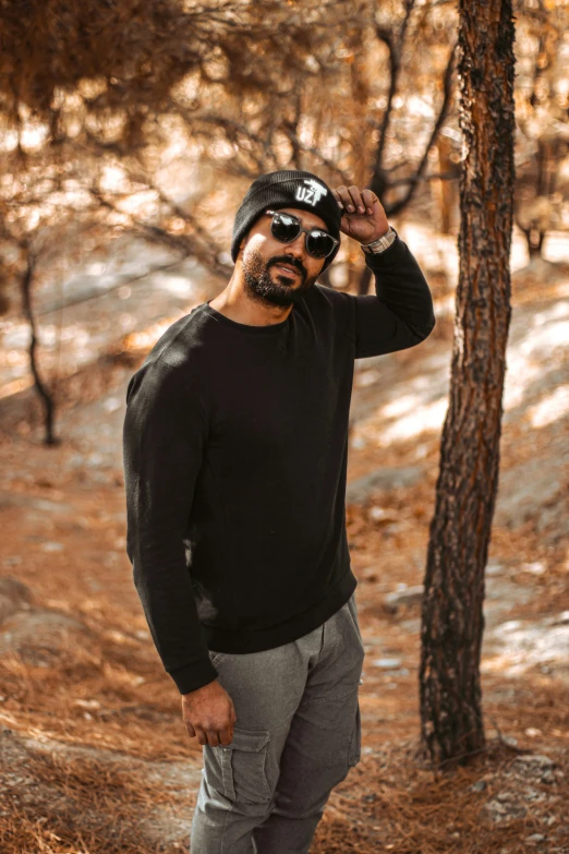 a man standing in a forest wearing glasses