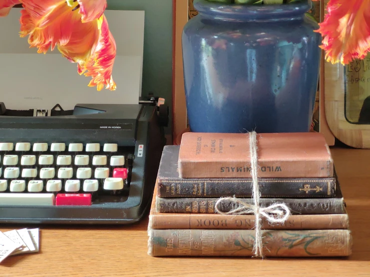 a pile of books and a typewriter on a desk