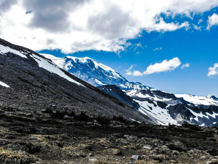 mountains under a partly cloudy blue sky with snow