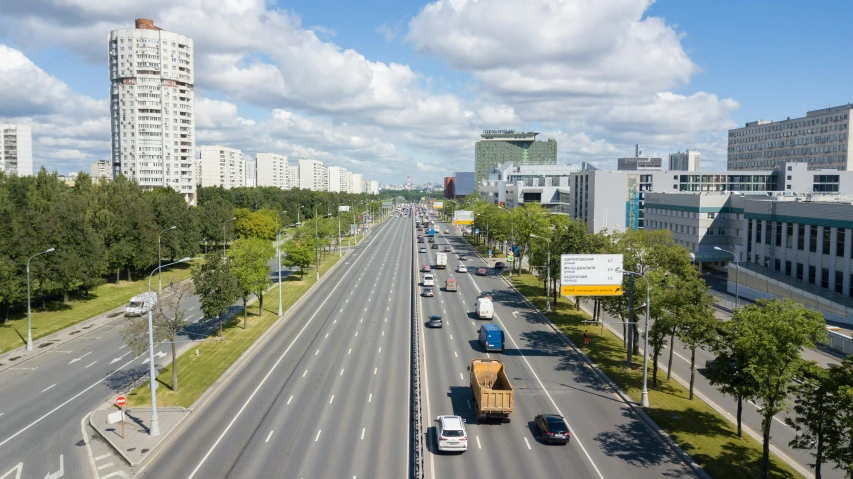 a wide road with traffic on it, passing buildings and street signs