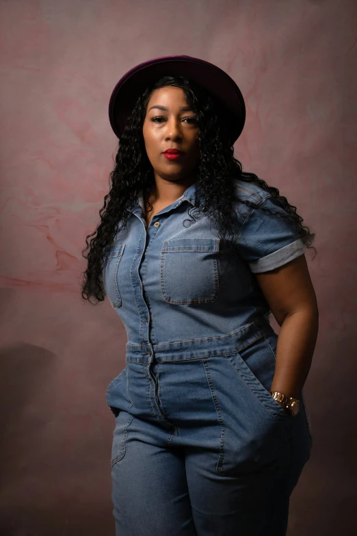 a black woman wearing overalls and a hat