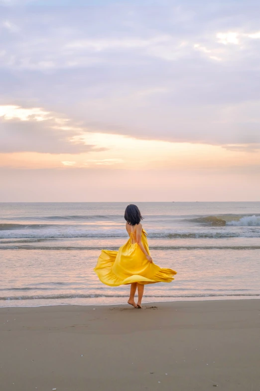 a woman in yellow standing on a beach