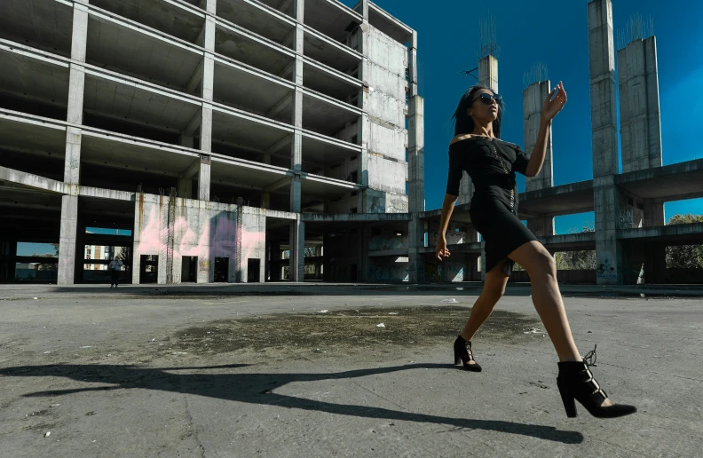 a woman wearing all black in front of an unfinished building