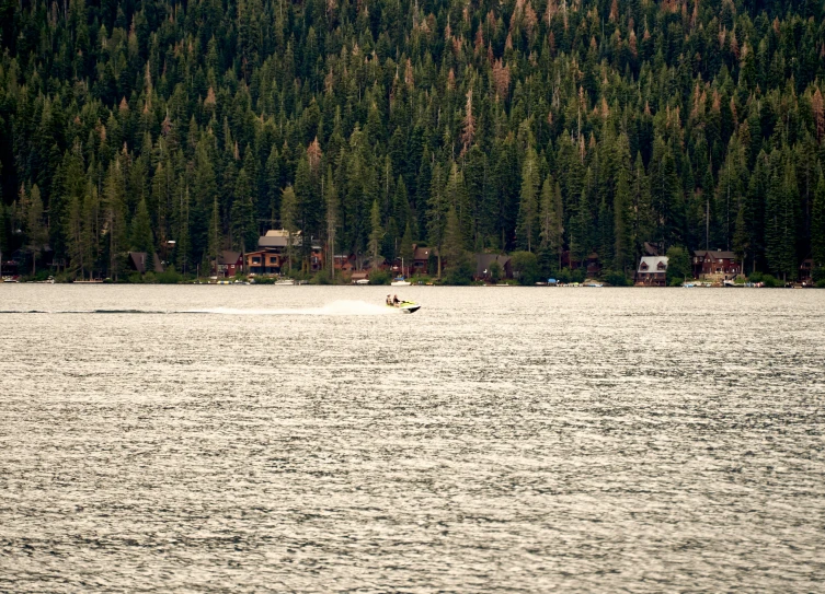 two people are skiing across the water near a forest