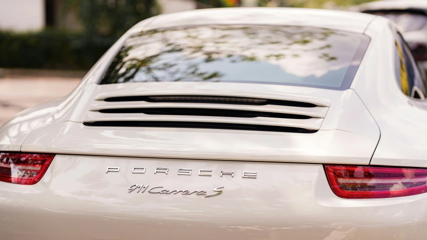 a white porsche parked near a sidewalk