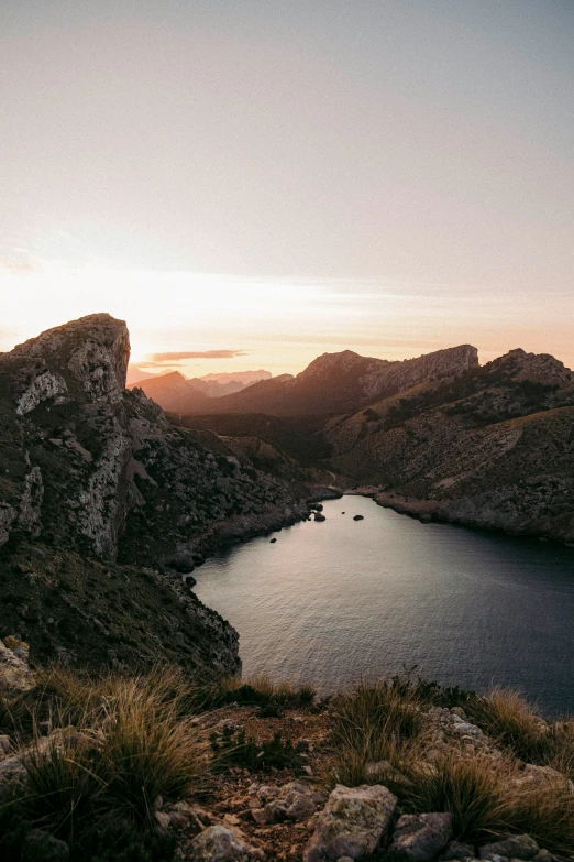 a lake in the middle of mountains with people sitting on top of it