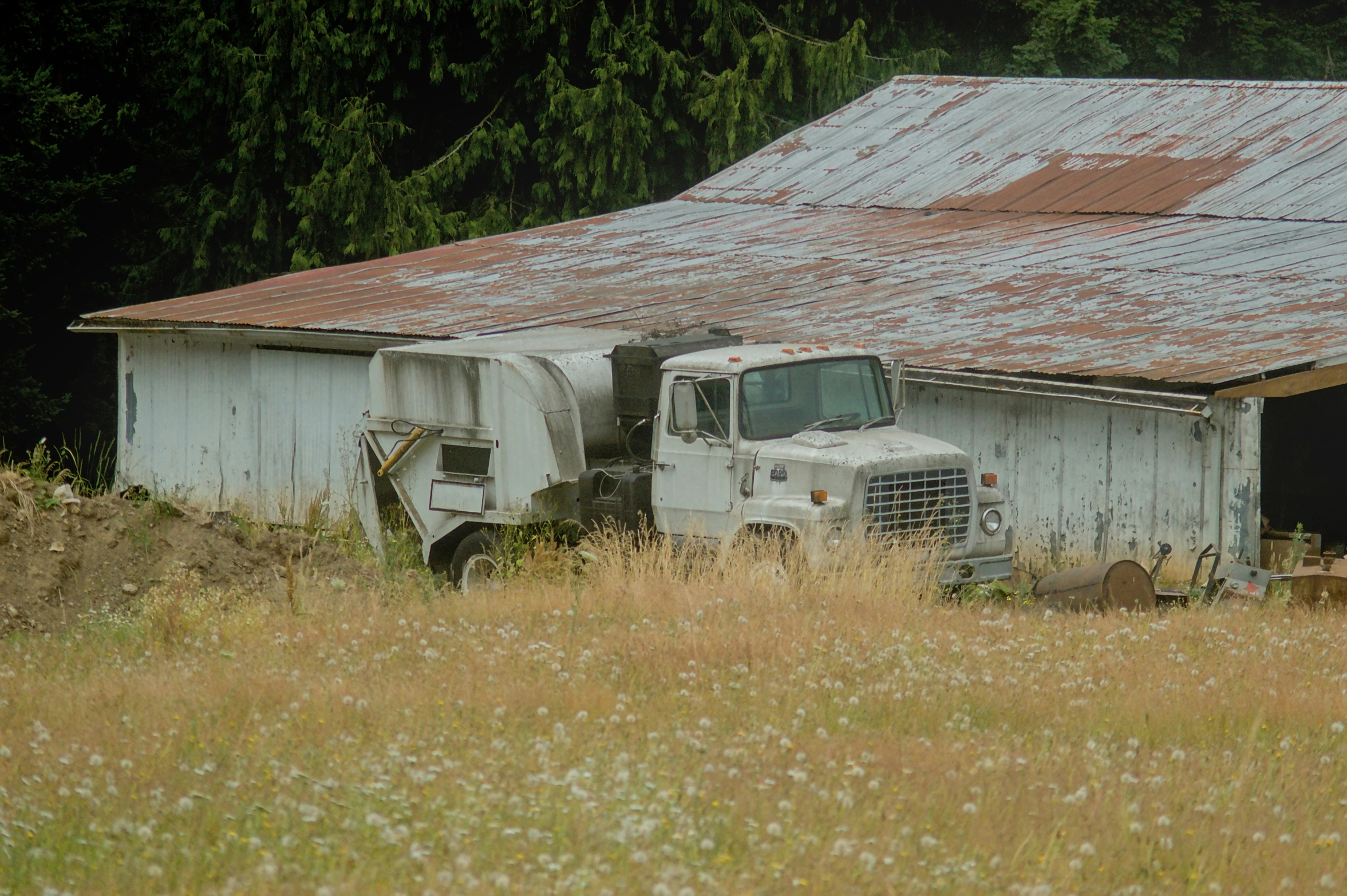 a tractor trailer parked in front of a white barn