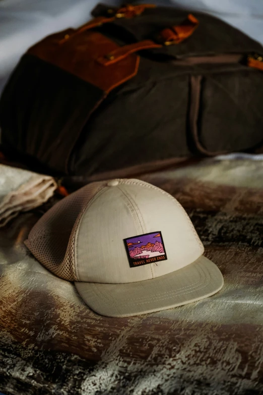 a white hat sits on a bed next to an open luggage bag