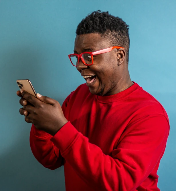 man in red sweater looking at phone while standing up