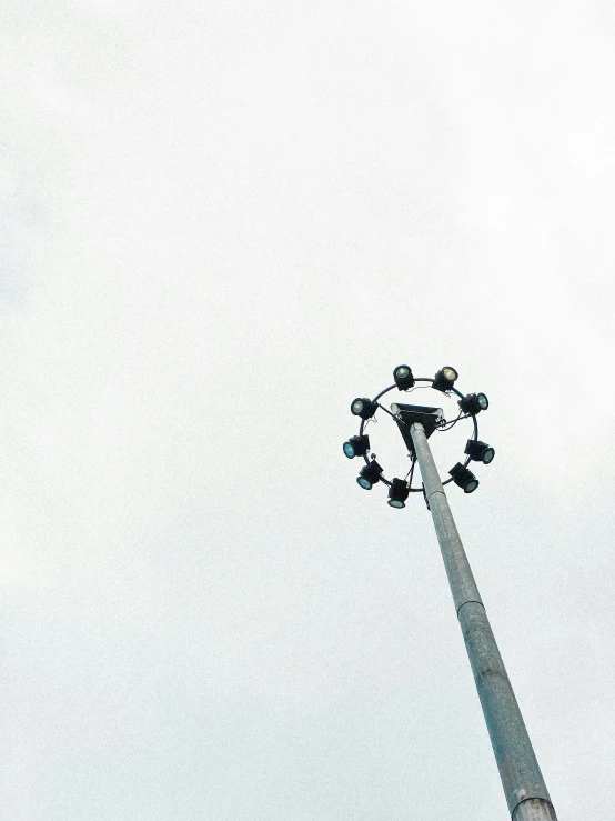 the large street light stands tall in front of the grey sky